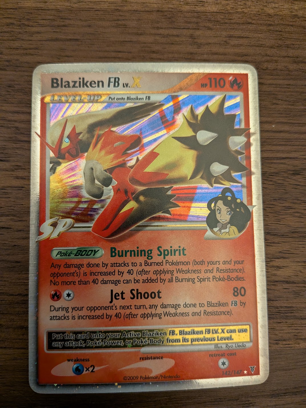 Phone photo of a holographic trading card lying on a wooden desk, ready to be graded